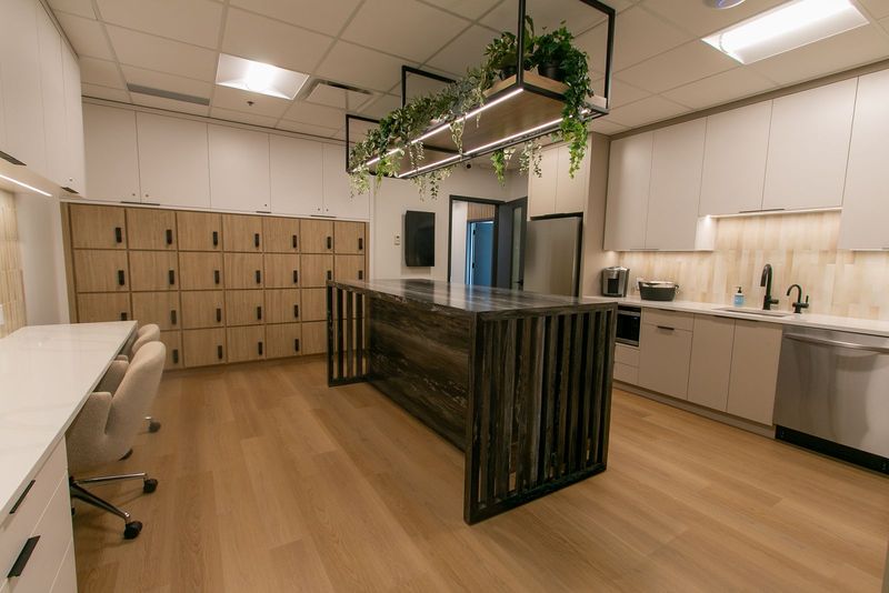 The Studio Hub with a kitchen island, wooden lockers, a kitchenette and a desk with chairs